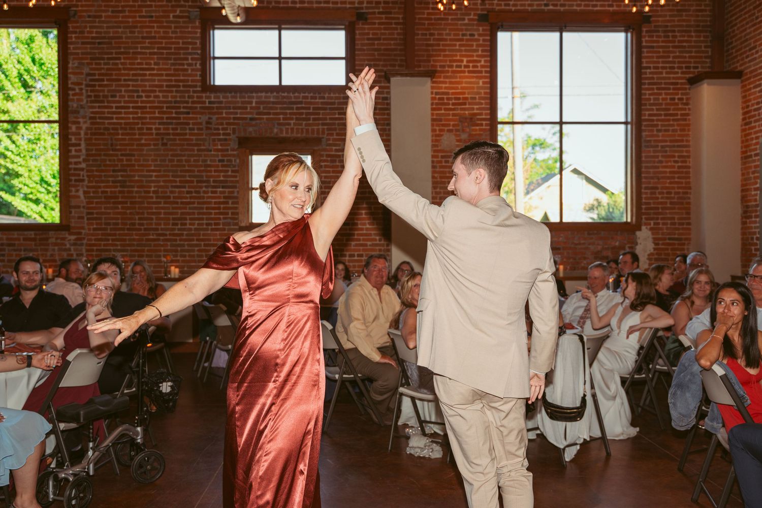 Dancing couples fill the dance floor at a wedding reception in an industrial-style venue.