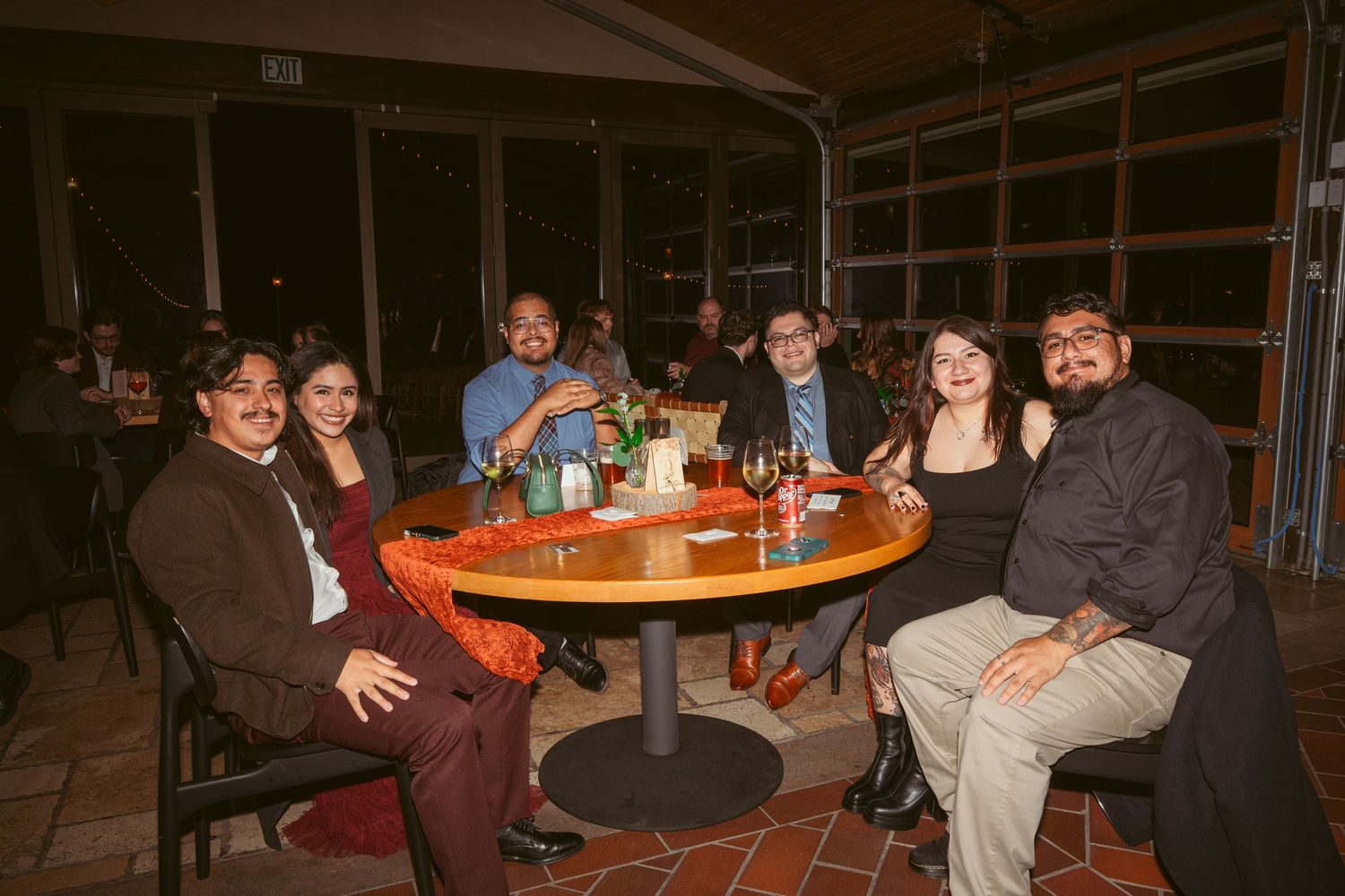 People enjoying conversation and drinks at round tables in a restaurant setting.