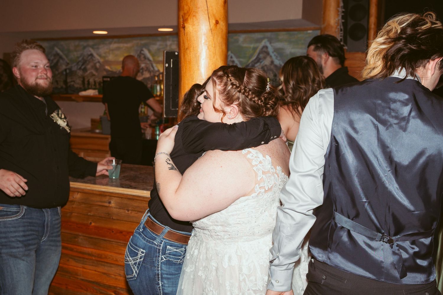 People dancing together in a rustic wooden interior during what appears to be a social gathering or celebration.