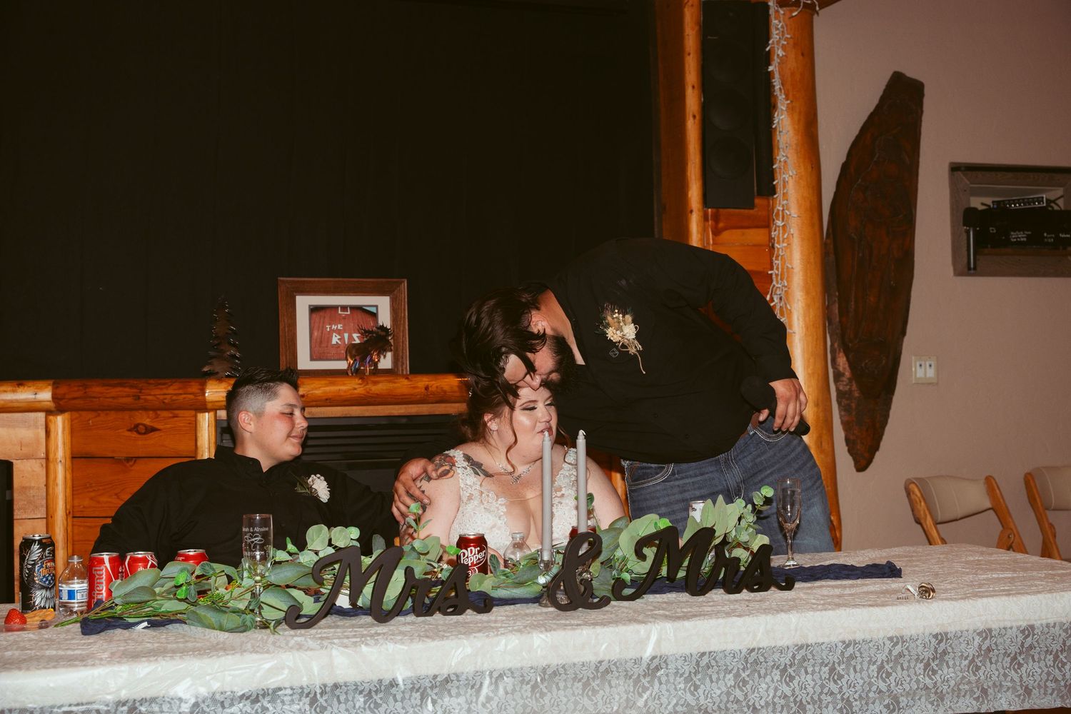 Wedding reception dinner setup with decorative table settings and lighting in rustic indoor venue.
