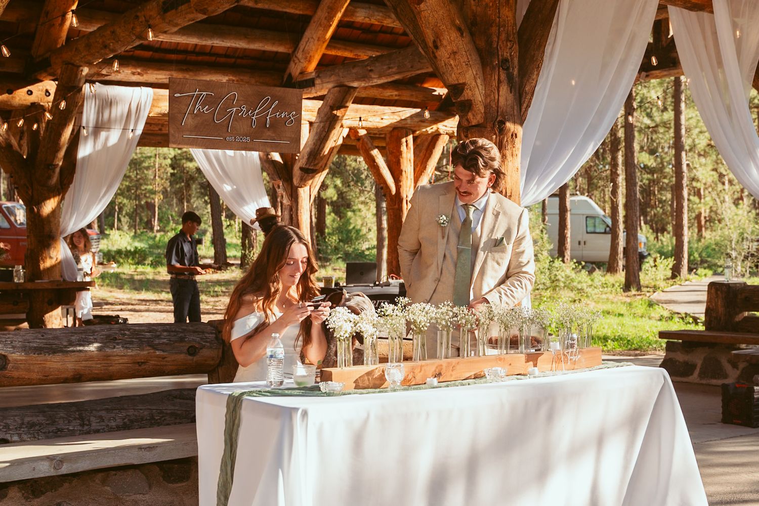 Rustic wooden pavilion decorated with white drapes for an outdoor wedding reception.