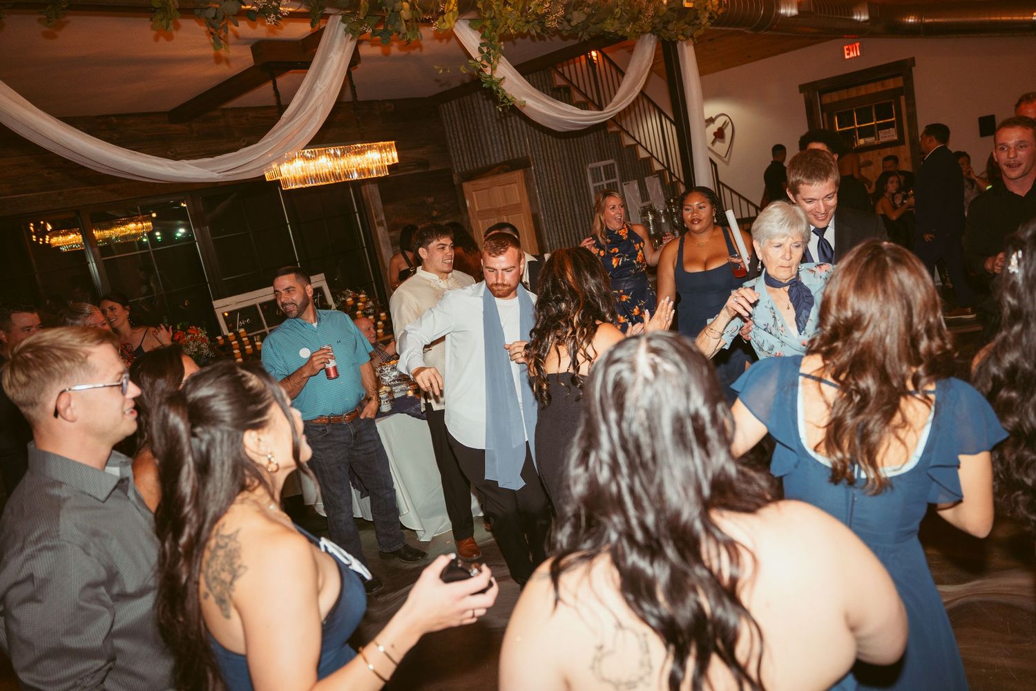Energetic crowd dancing and mingling at an evening celebration with decorative lighting.