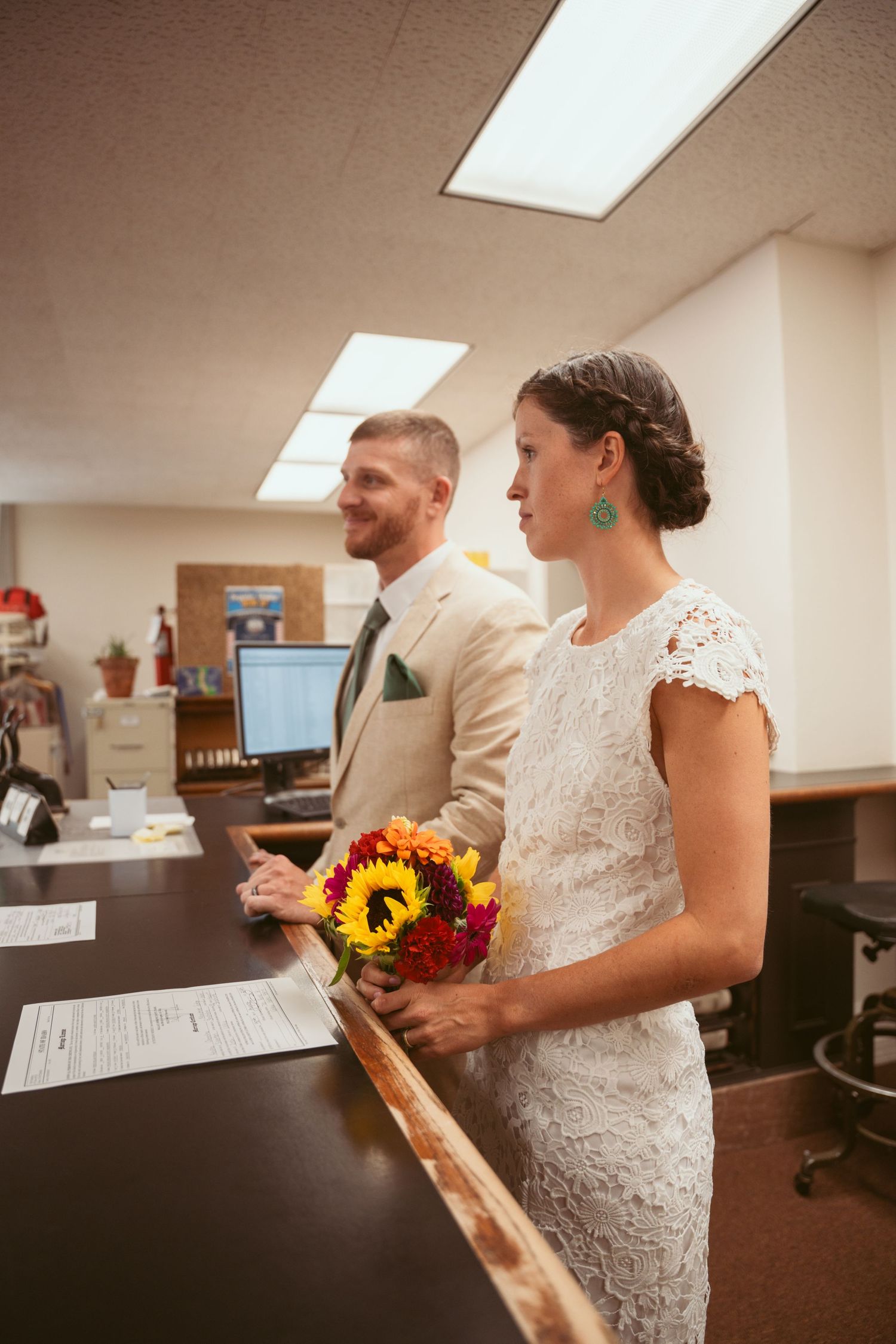 A couple stands at a counter holding colorful sunflower bouquets.