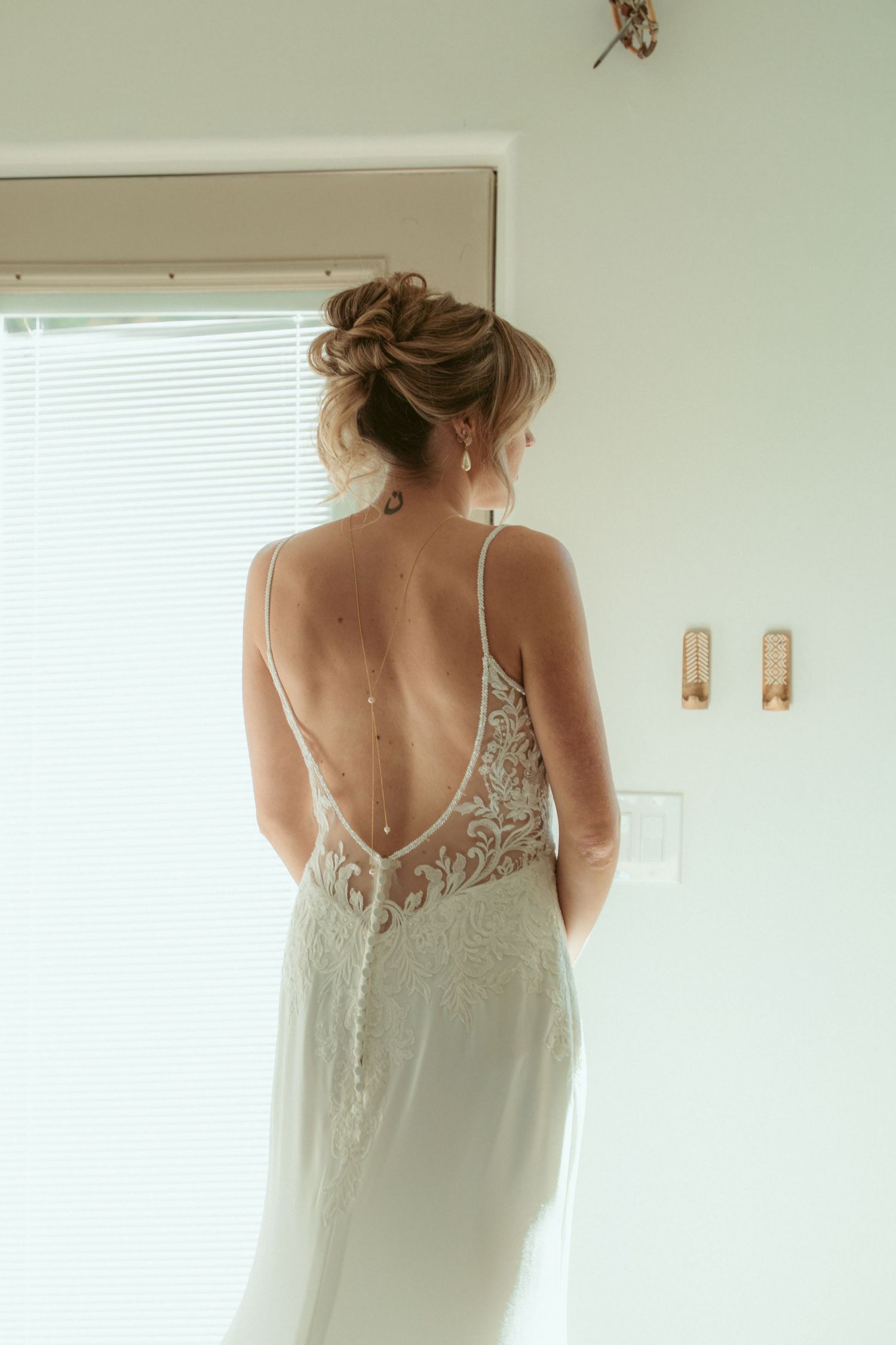 Back view of a bride in a delicate lace wedding gown with open back design.