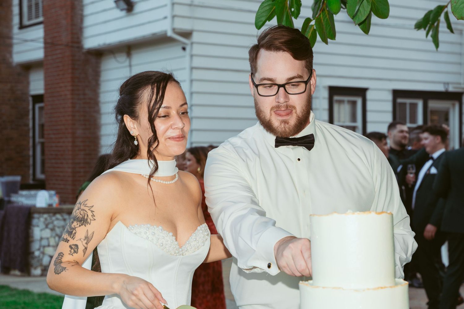 A wedding couple cuts their white tiered cake together at their reception.