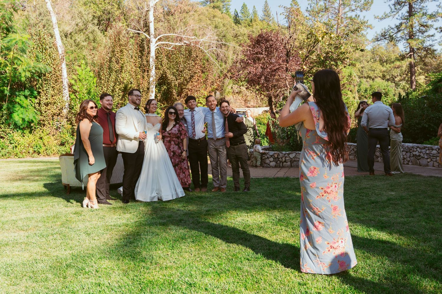 Outdoor wedding ceremony setup with green lawn and trees in natural sunlight.