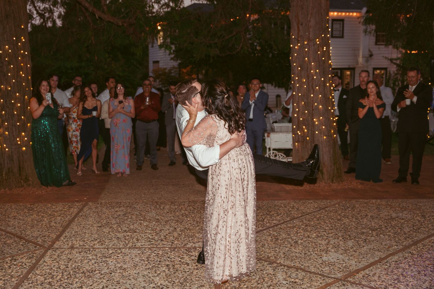 A couple shares an intimate dance moment at their evening outdoor reception.
