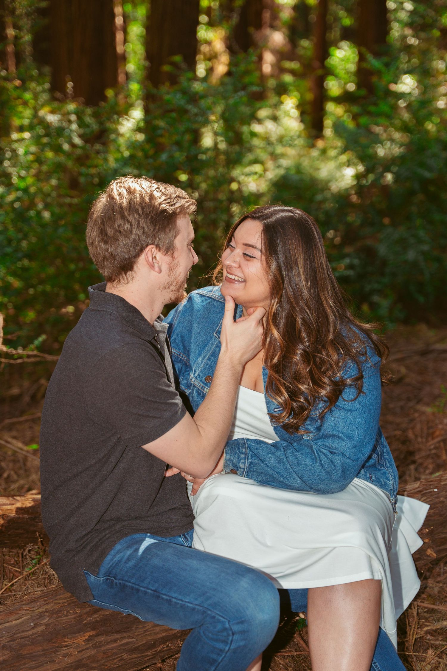 Couple lounging together on white blanket in dappled forest sunlight.