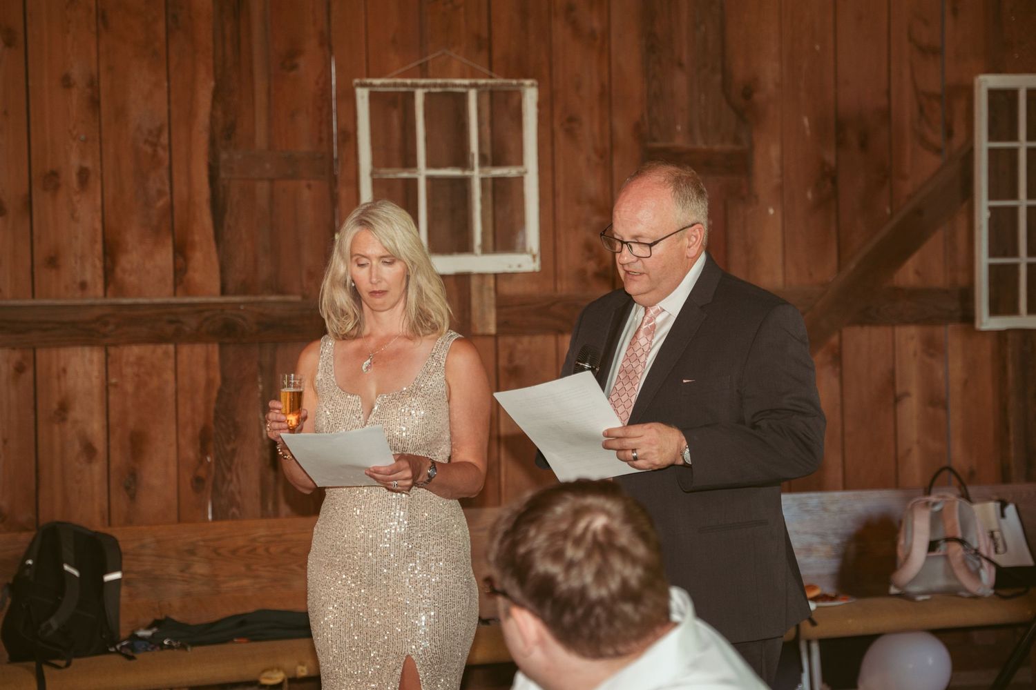 Wedding speeches being delivered in rustic barn venue with string lights and wooden walls.