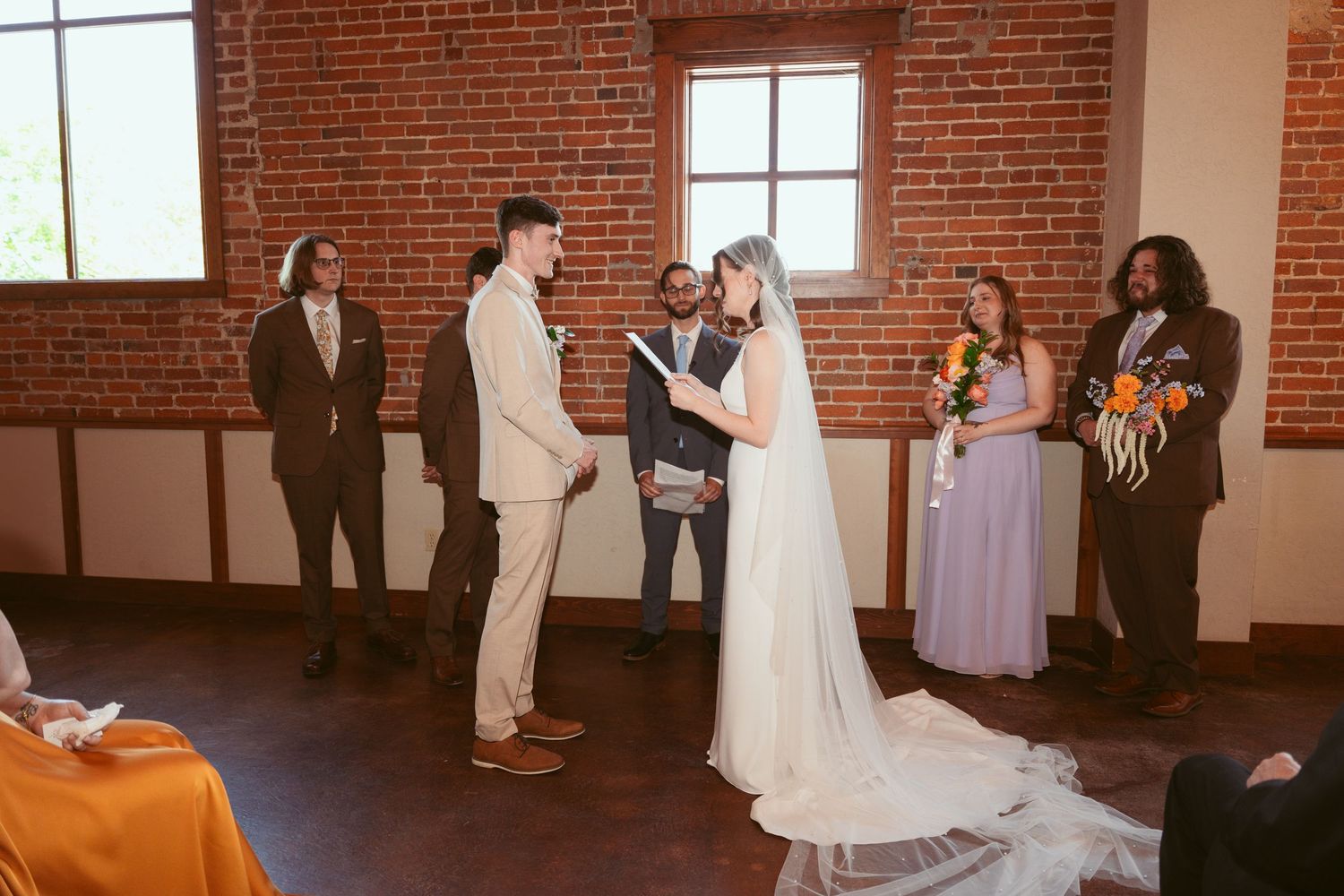 Wedding party standing in formation during ceremony in historic brick building.