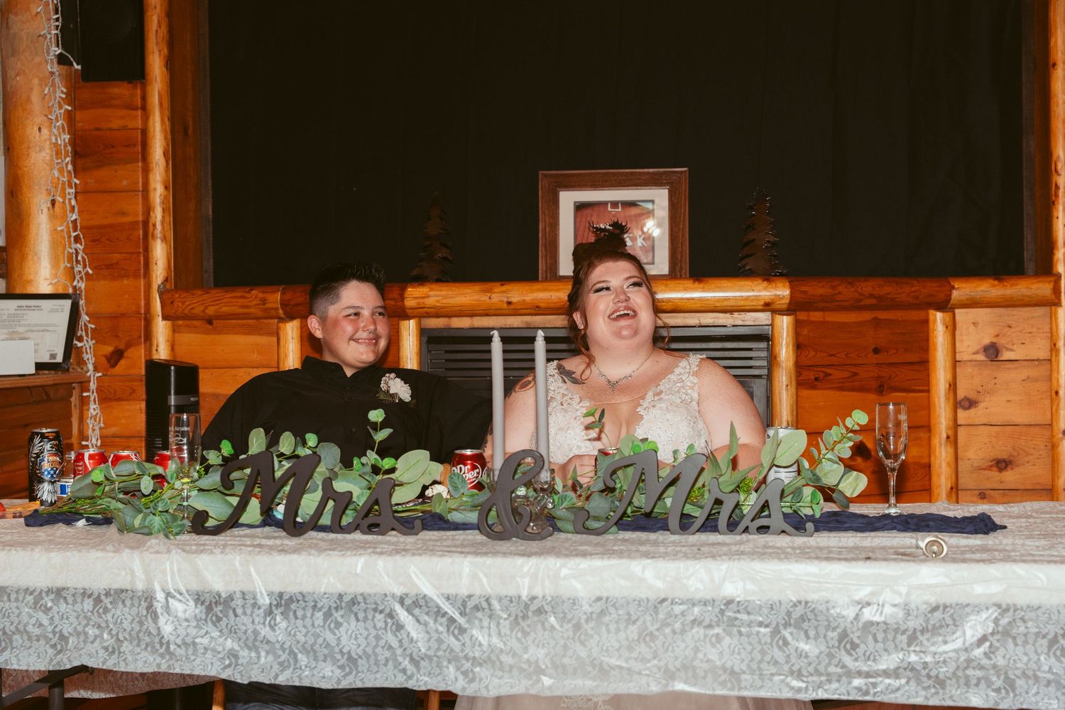 Long wooden table decorated with greenery garlands in a rustic venue setting.