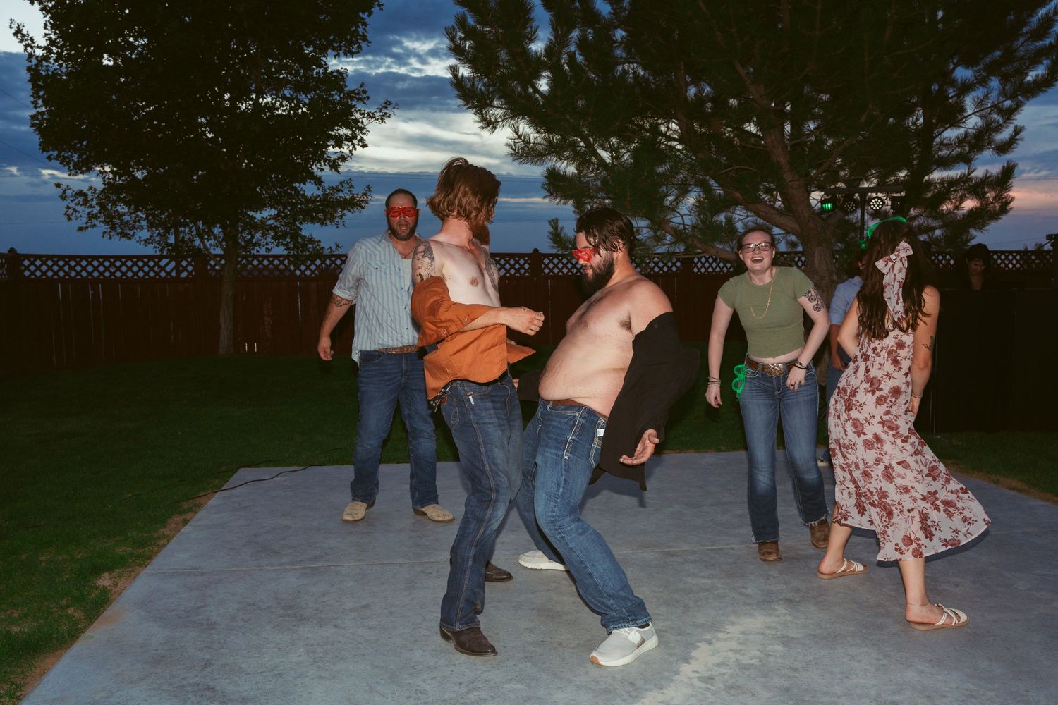 Wedding party members perform synchronized dance moves on an outdoor patio.
