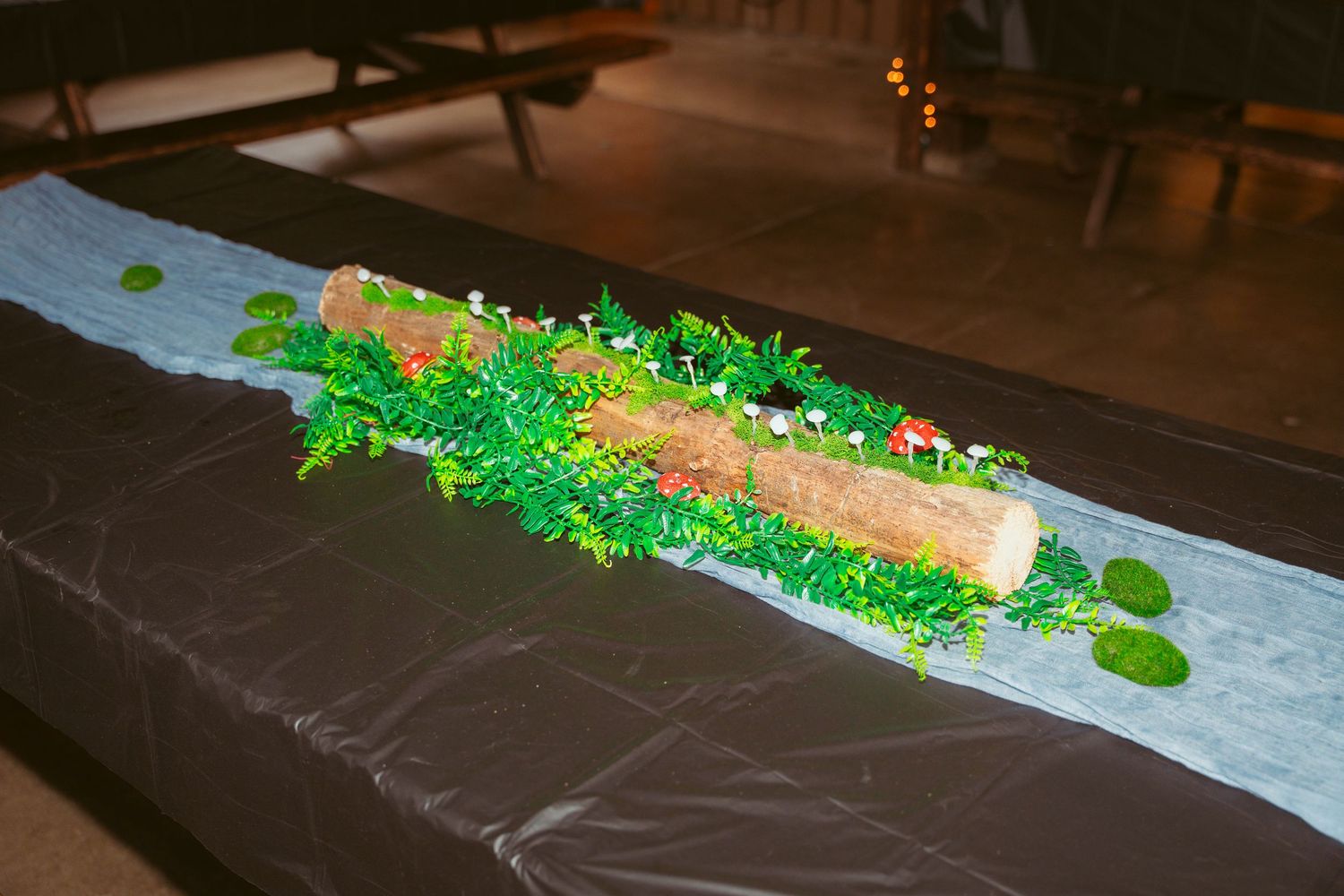 Long rustic table decorated with greenery and table settings for a wedding reception.