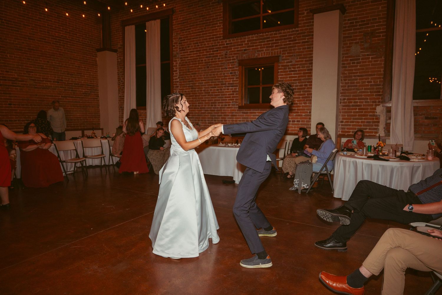 Wedding celebration with dancing in an industrial-style venue with exposed brick walls.