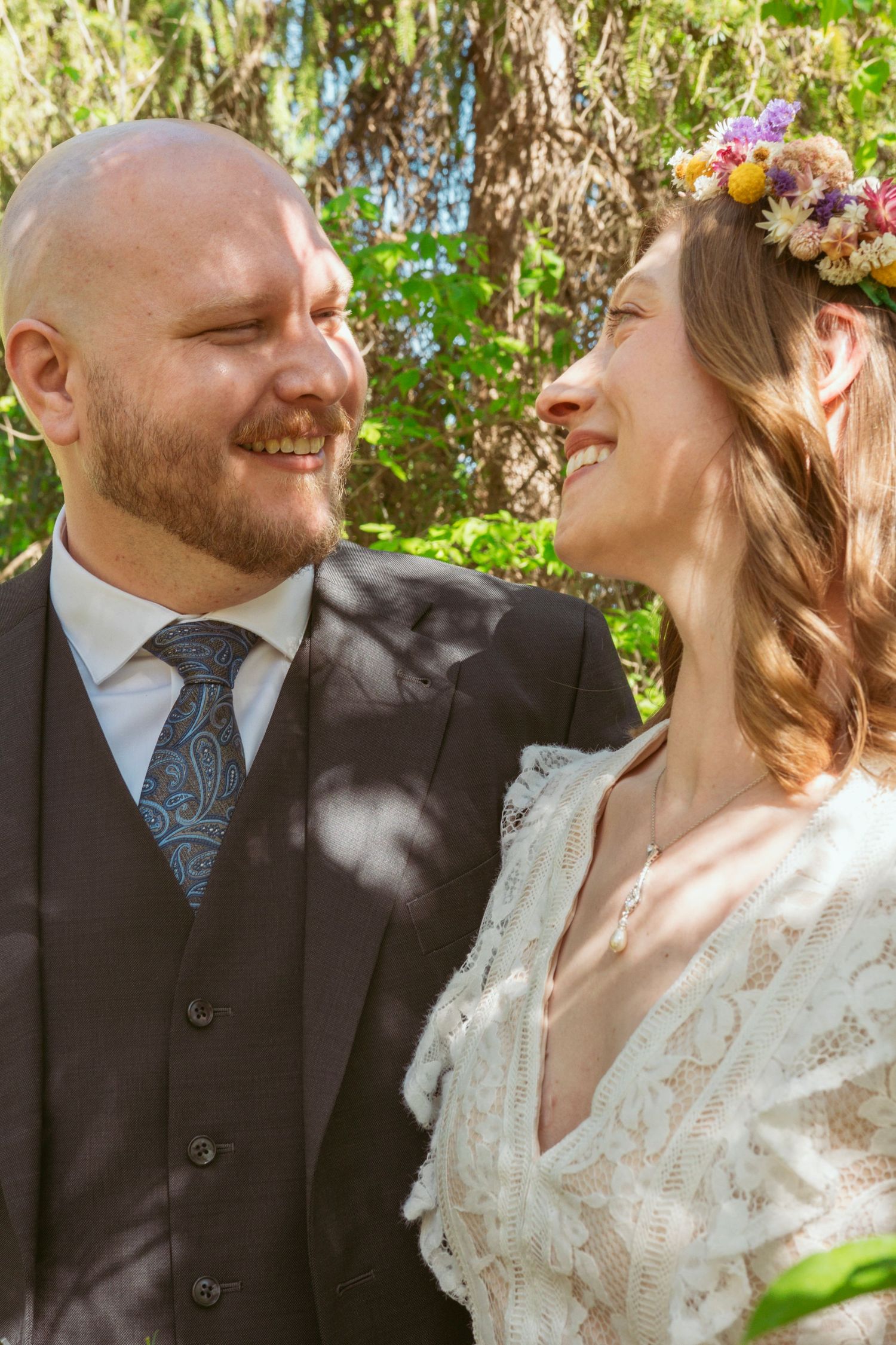 Sunlit wedding portraits in a garden setting with natural lighting and spring blooms.