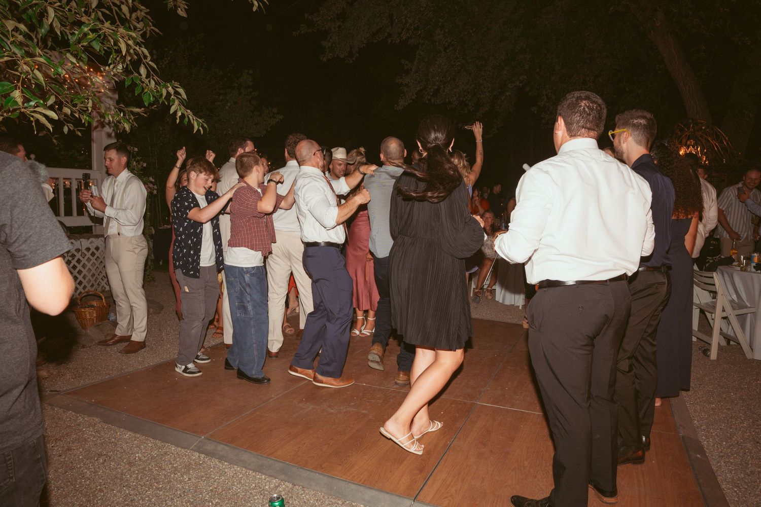 Guests mingling and dancing at an outdoor evening wedding reception.