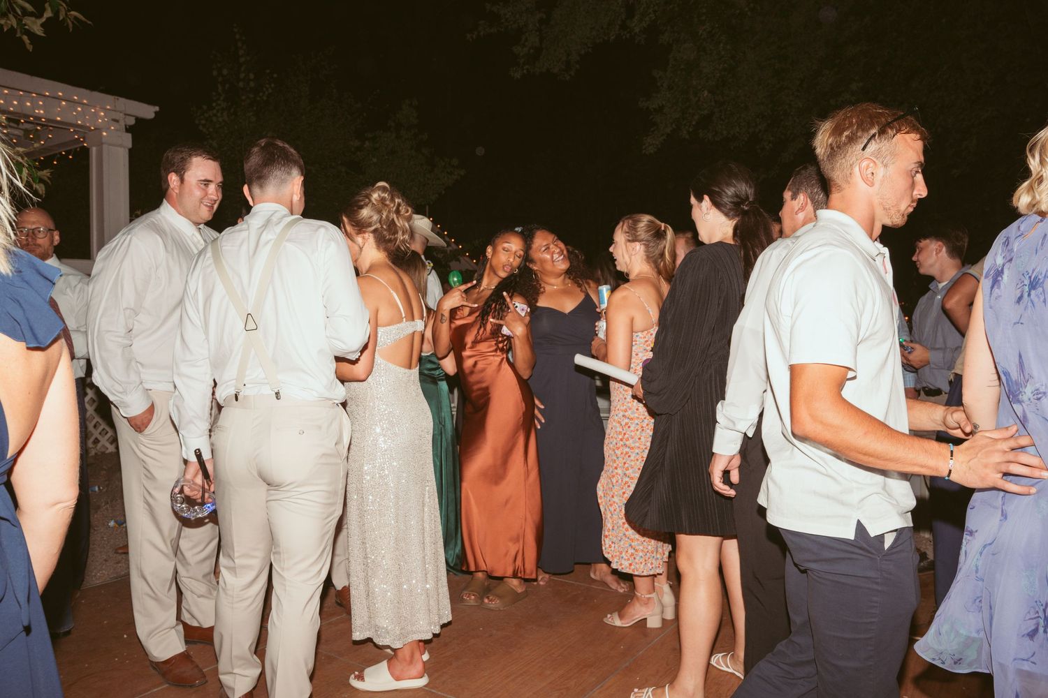 Wedding party guests dancing and celebrating on an outdoor dance floor at night.