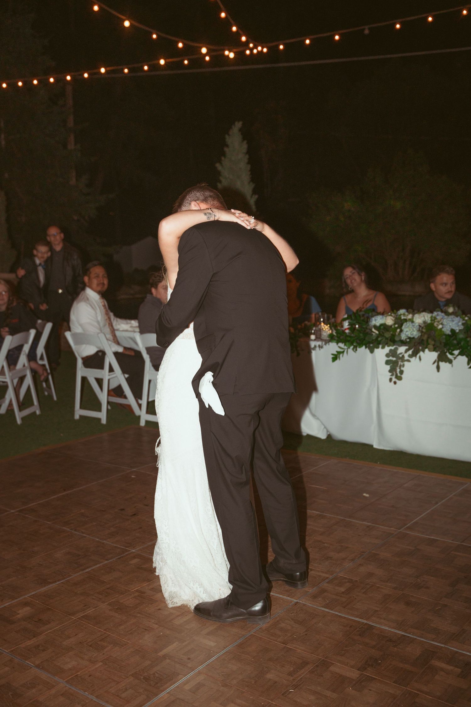 Couple dances together on a tiled outdoor patio under romantic string lights.