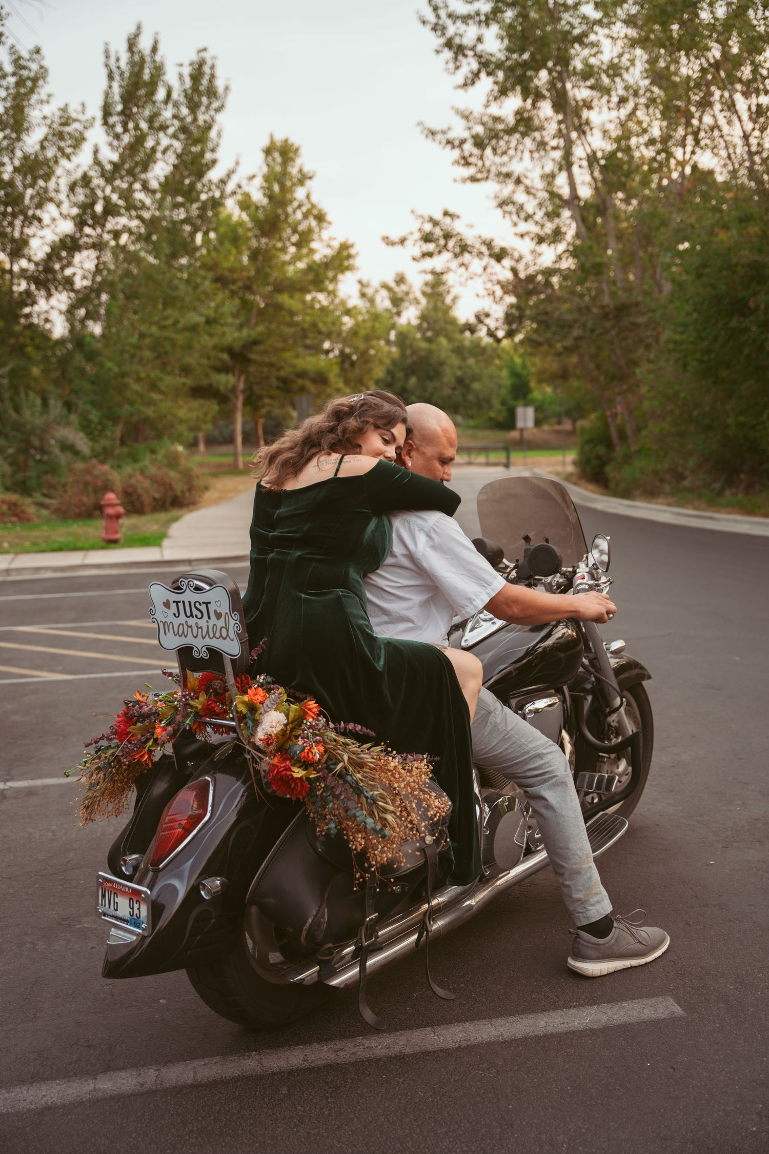 A motorcycle decorated with flowers parked in an outdoor lot during a photoshoot.
