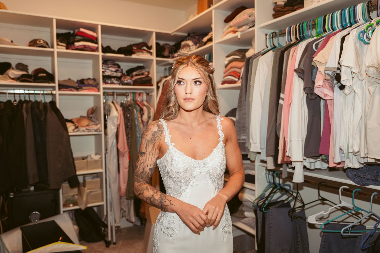 A person in a light-colored dress stands in a spacious walk-in closet filled with hanging clothes.