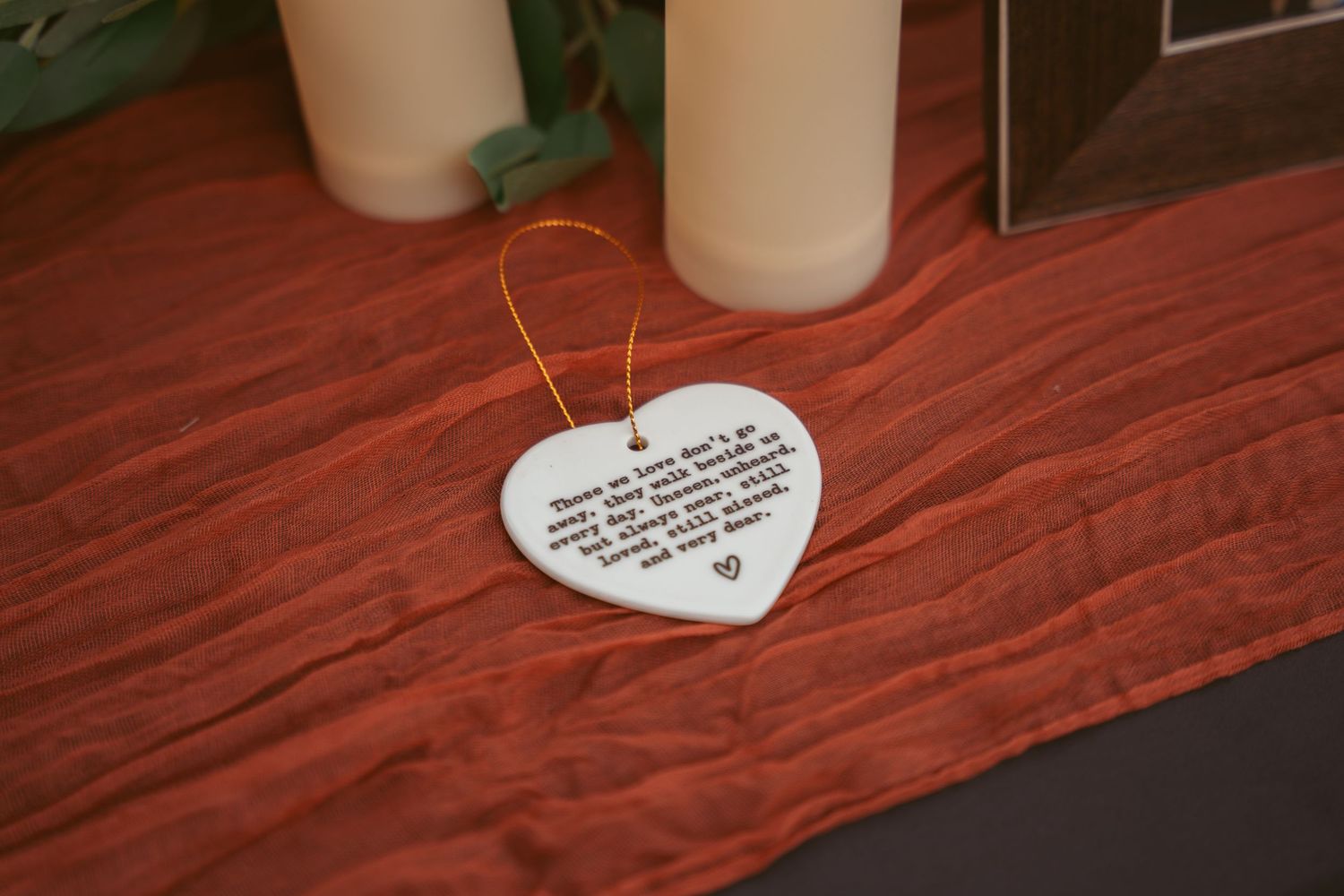 Close-up of wedding decor featuring heart-shaped notes and white pillar candles on a red surface.