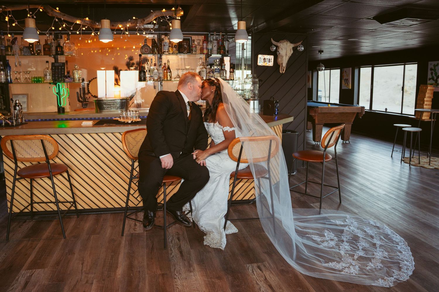 A romantic wedding moment in a rustic bar setting with a long flowing veil.