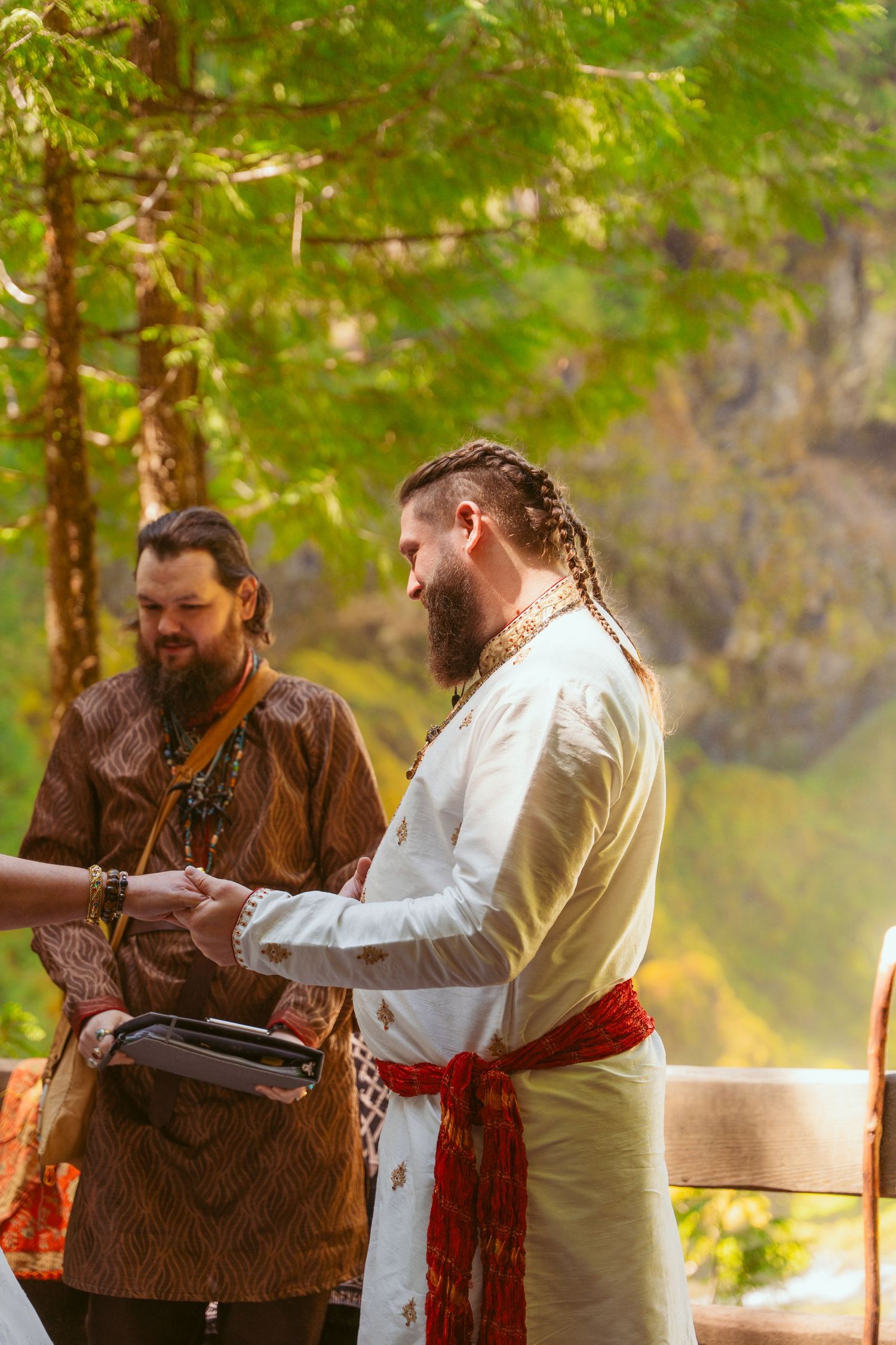 Medieval-themed wedding participants in traditional garb interact during forest ceremony.