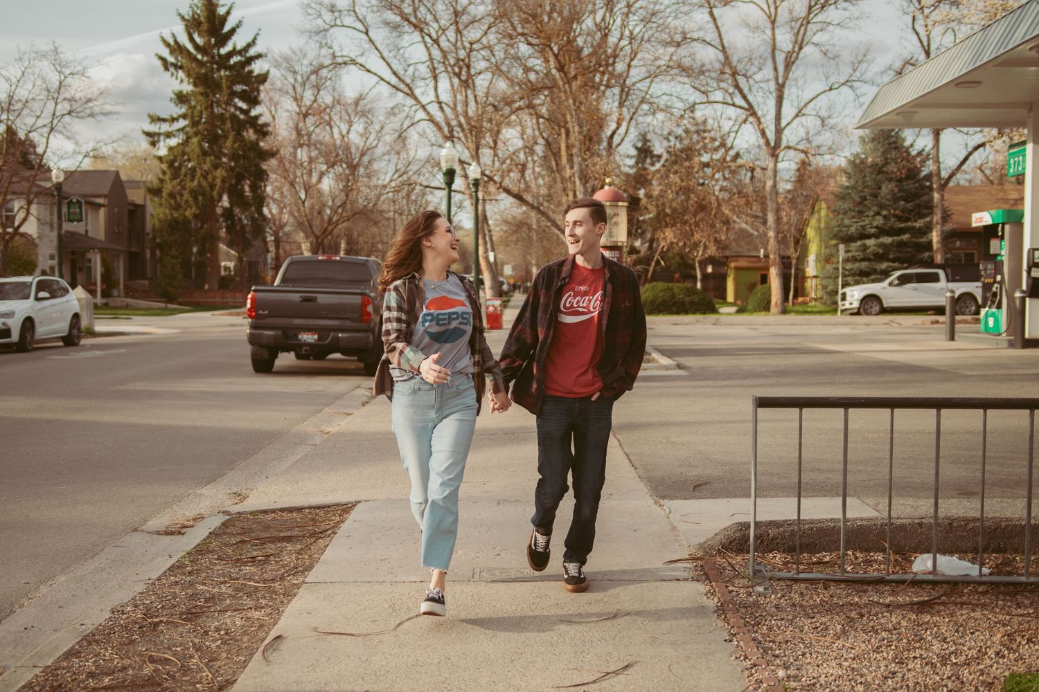 Two people stroll down a suburban street with bare trees in the background.