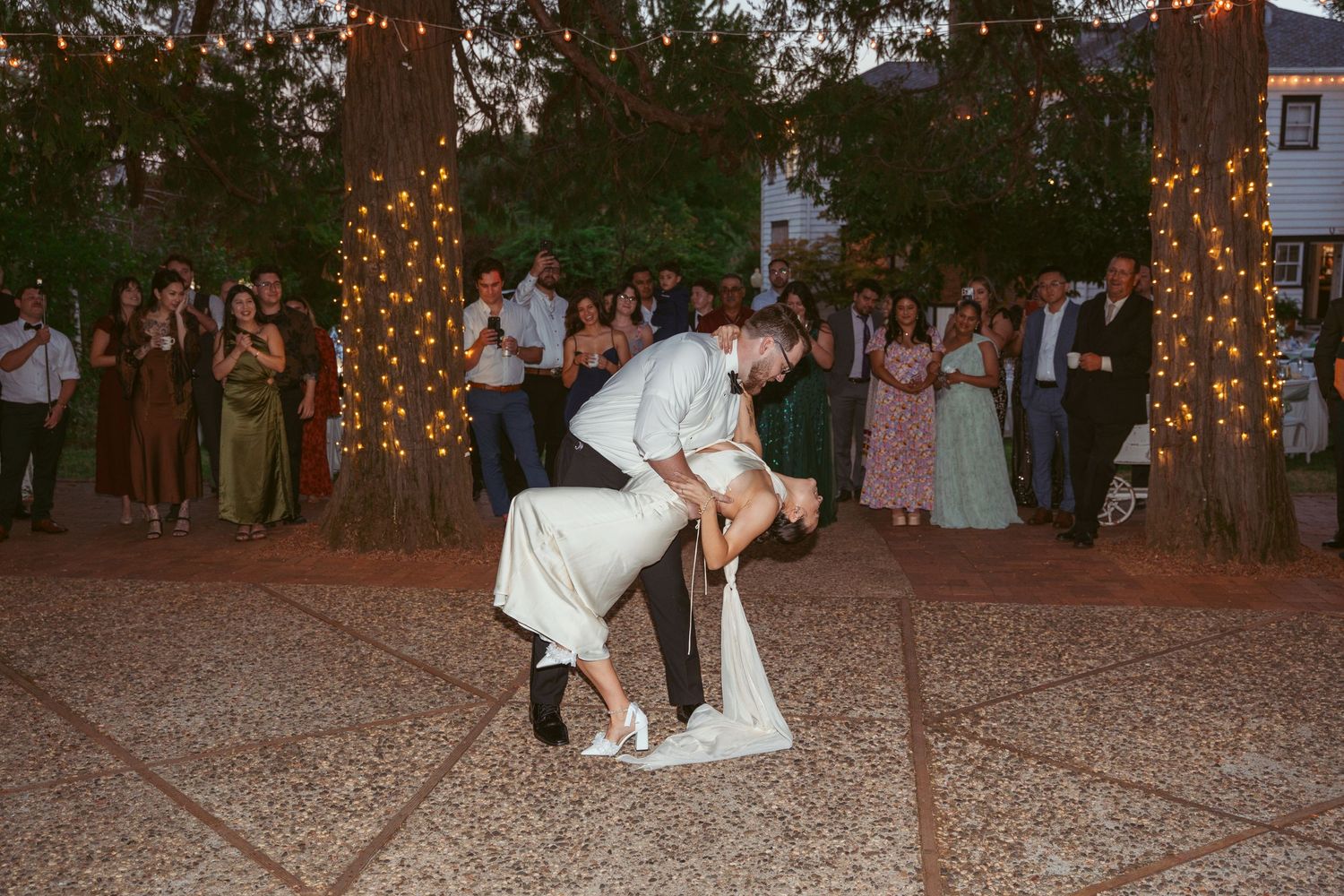 Evening wedding reception with string lights illuminating outdoor dance floor.