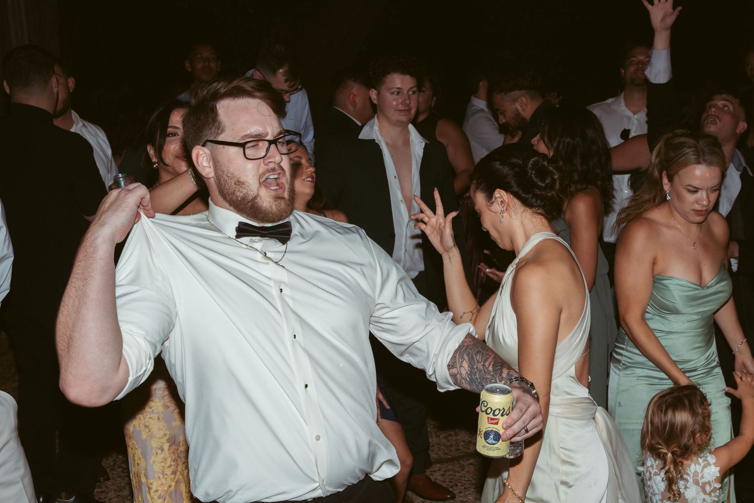 Wedding guests dancing enthusiastically on the dance floor during an evening reception.