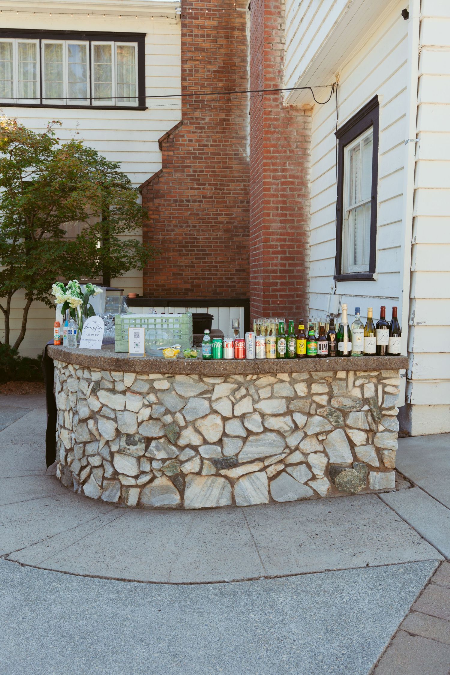 Exterior view of a white building with brick columns and decorative stone wall.