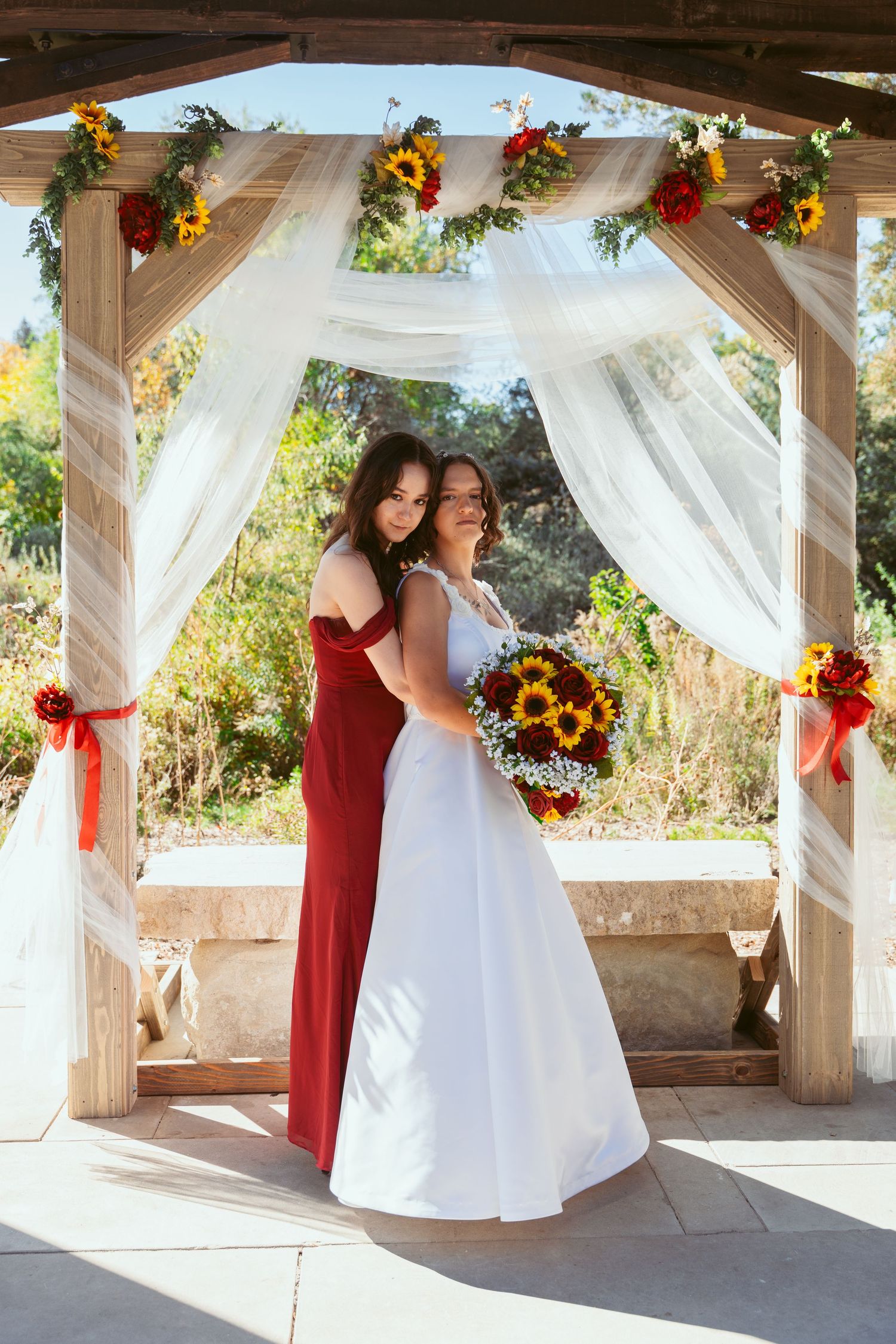 Candid wedding moments captured under a wooden pavilion with flowing white fabric and floral decorations.