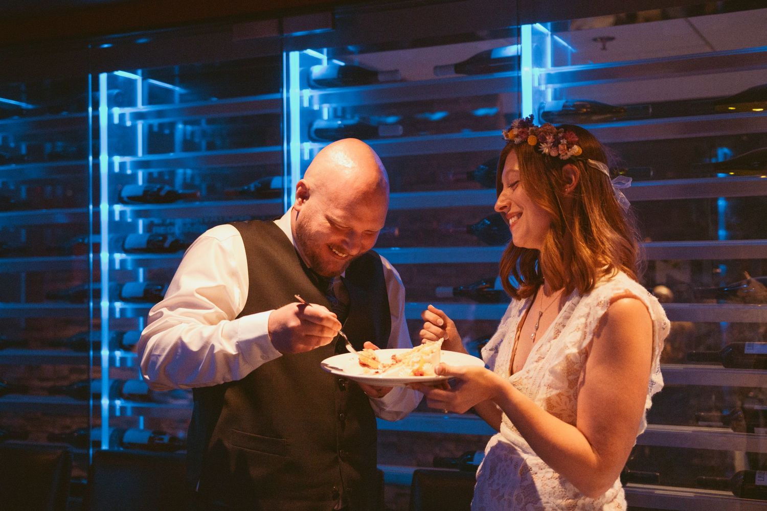 Intimate wedding reception dinner illuminated by blue ambient lighting.