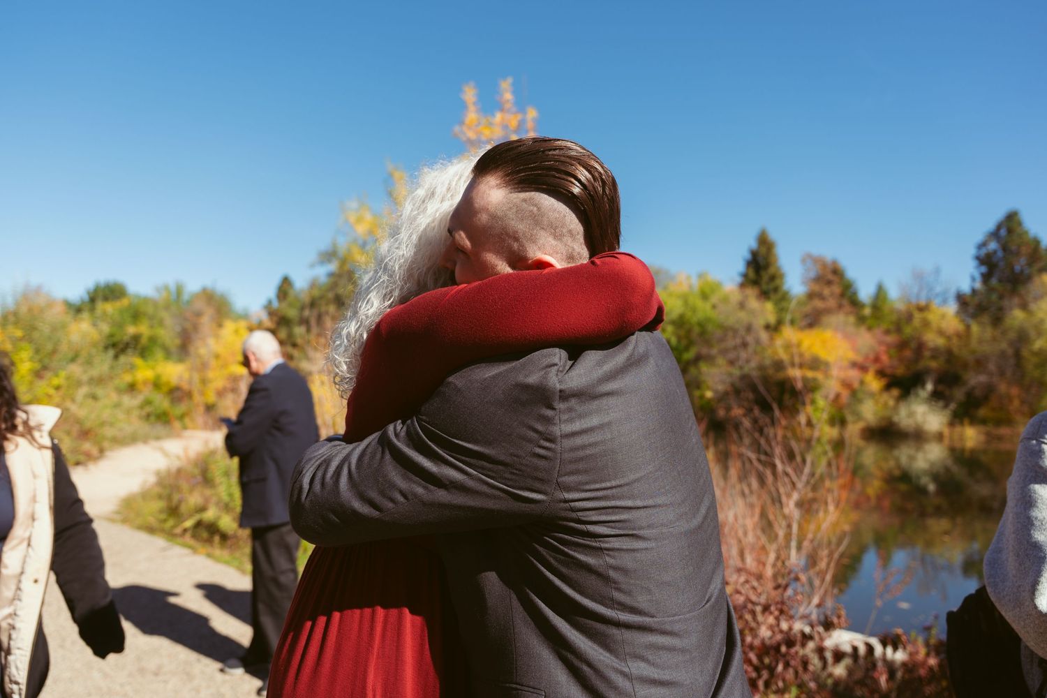 Wedding party hugs and celebrates together in a scenic outdoor fall setting.