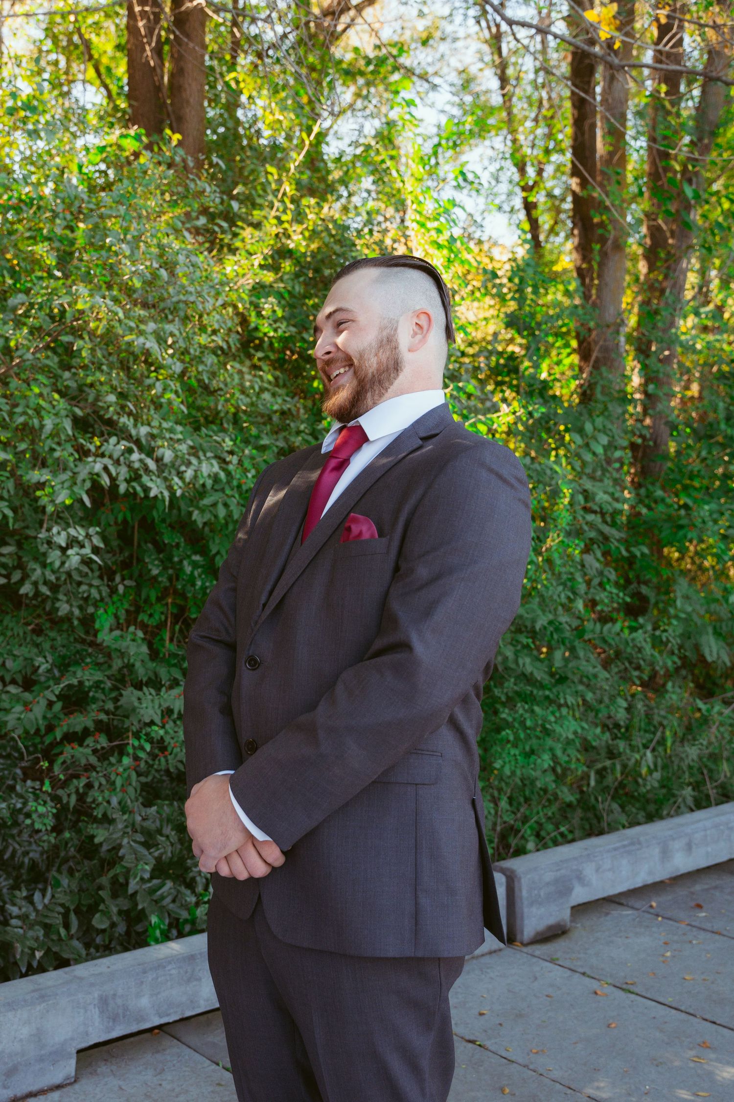 Wedding party members in dark suits standing on an outdoor path.