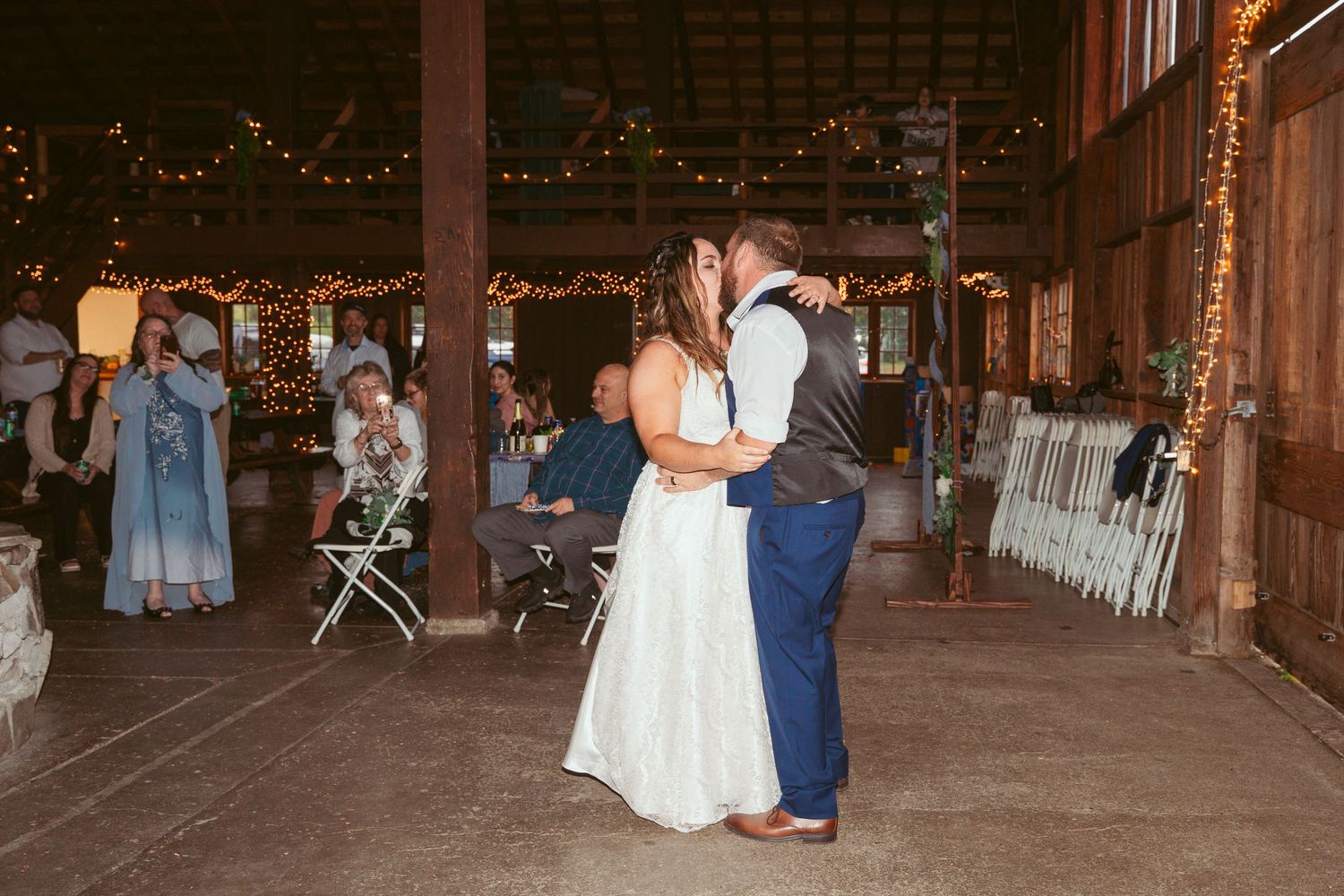 Wedding reception in a rustic barn venue decorated with string lights.