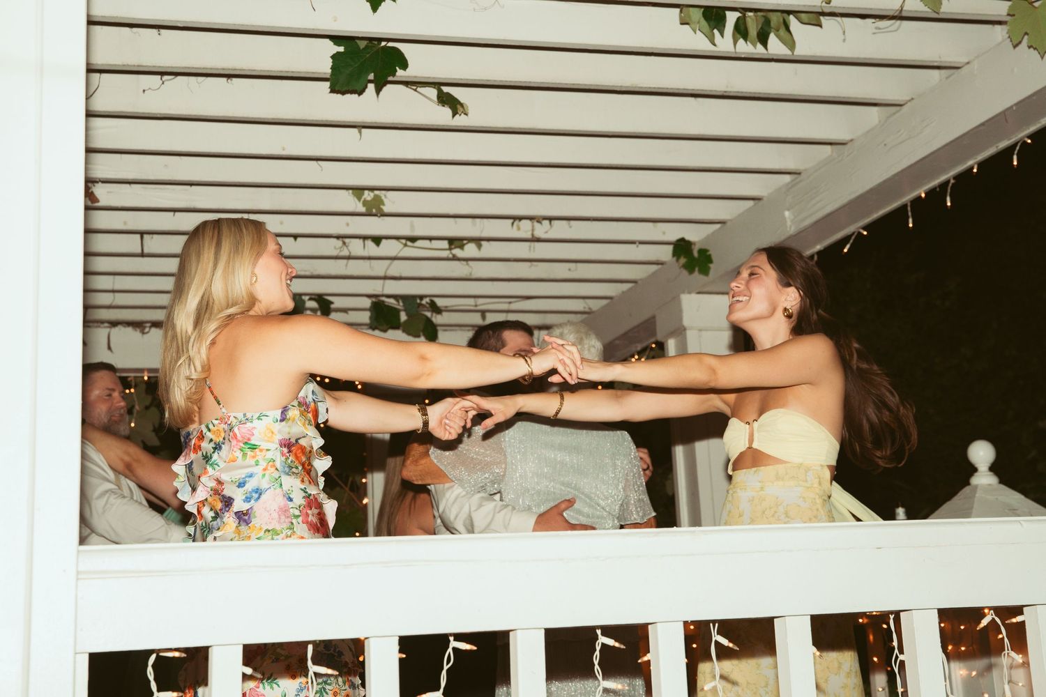 Wedding reception dance floor under a white pergola with guests celebrating.