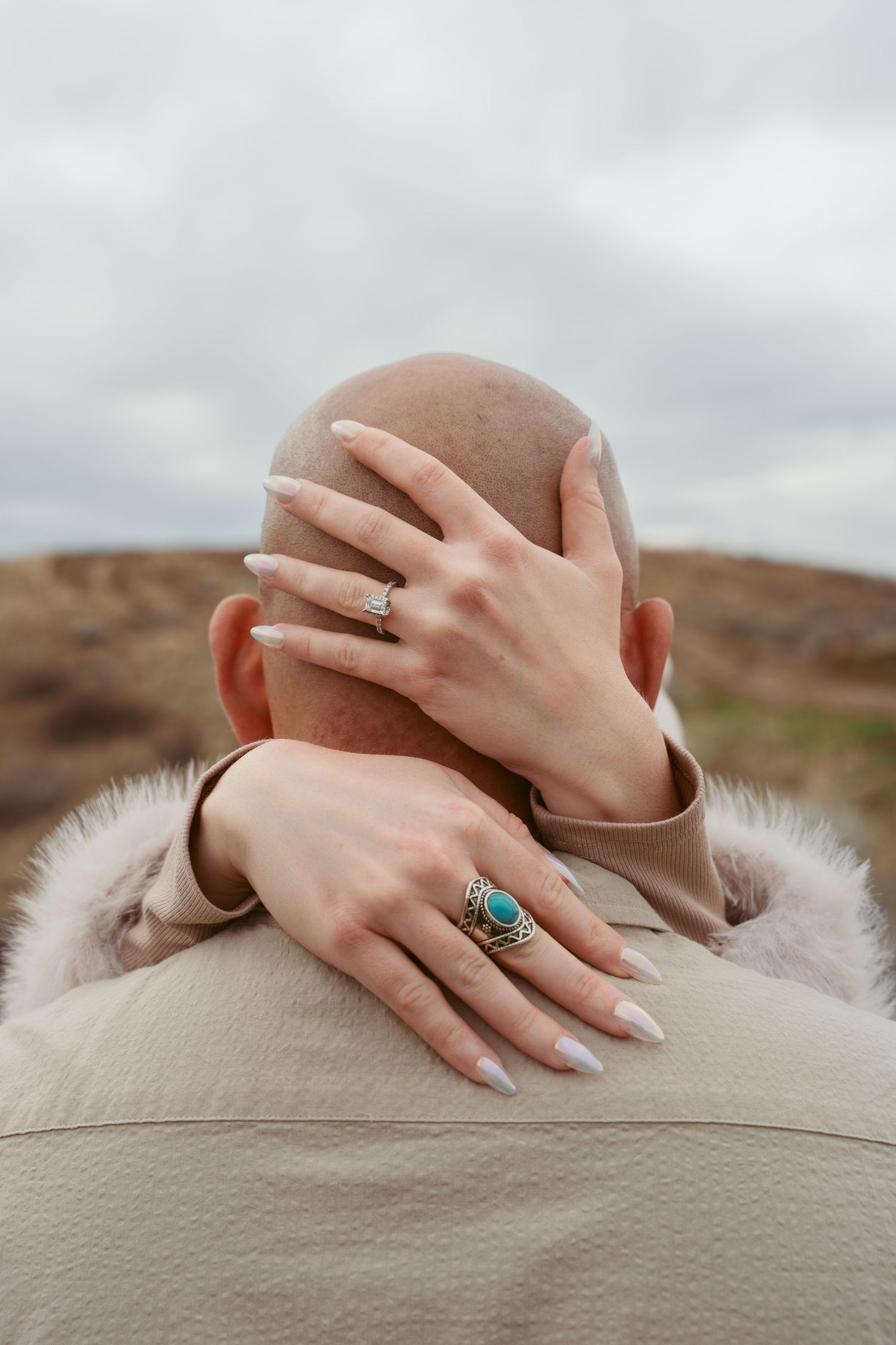 Close up detail of hands with rings against a soft beige background.