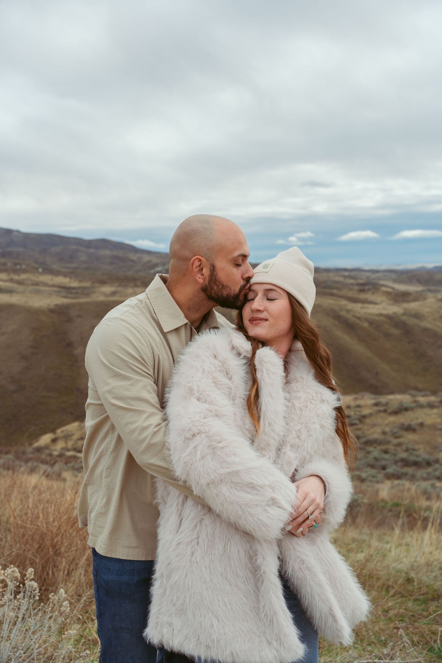 A tender moment captured between two people on a desert hillside.