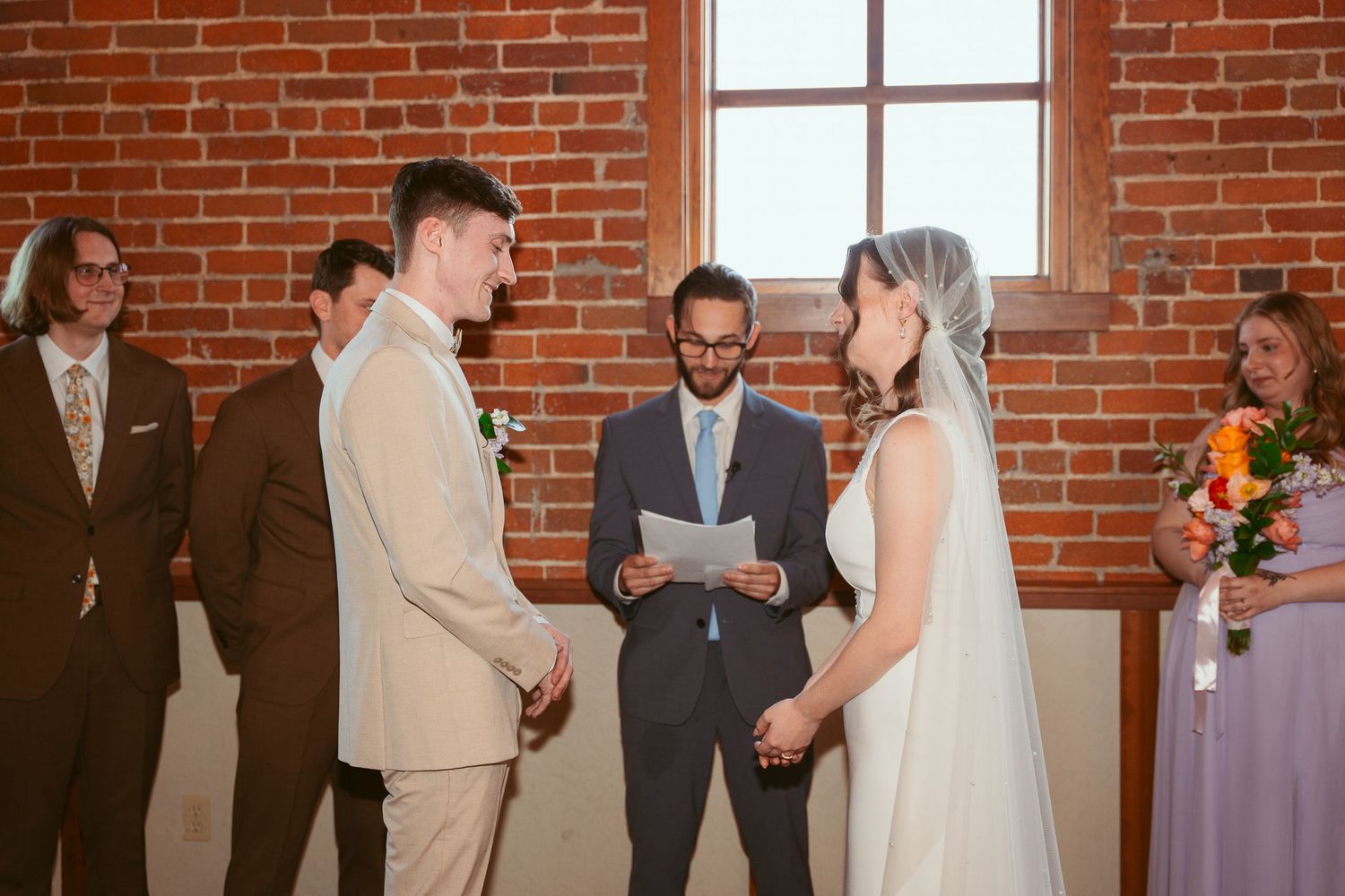 Emotional wedding ceremony moment captured in rustic brick venue with guests looking on.