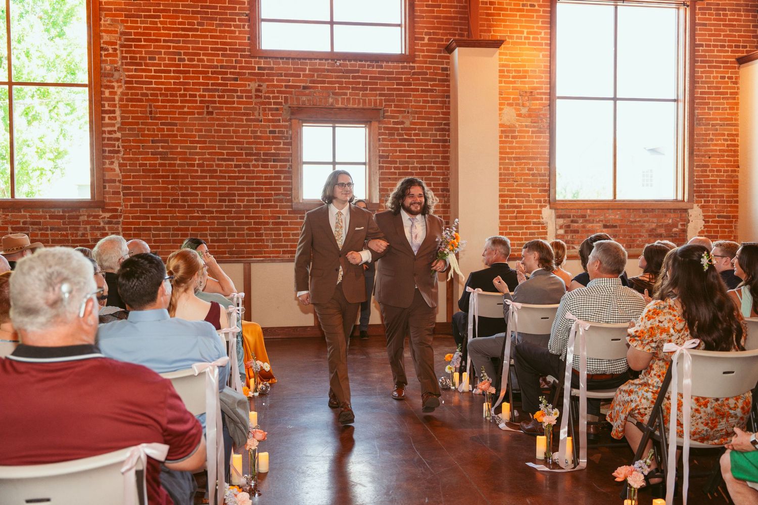 Industrial chic wedding venue with exposed brick walls and rows of white chairs for guests.