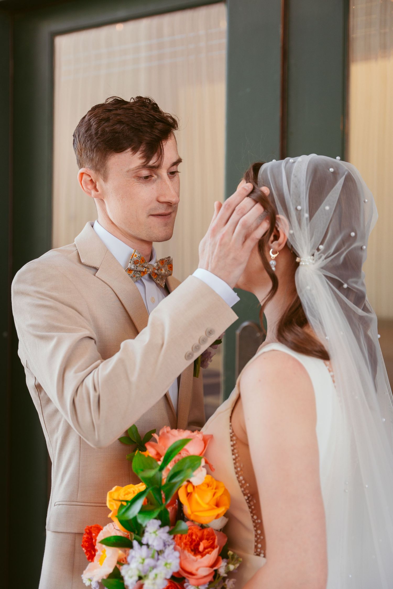 Intimate wedding portrait sequence with bright orange and coral florals against a window.