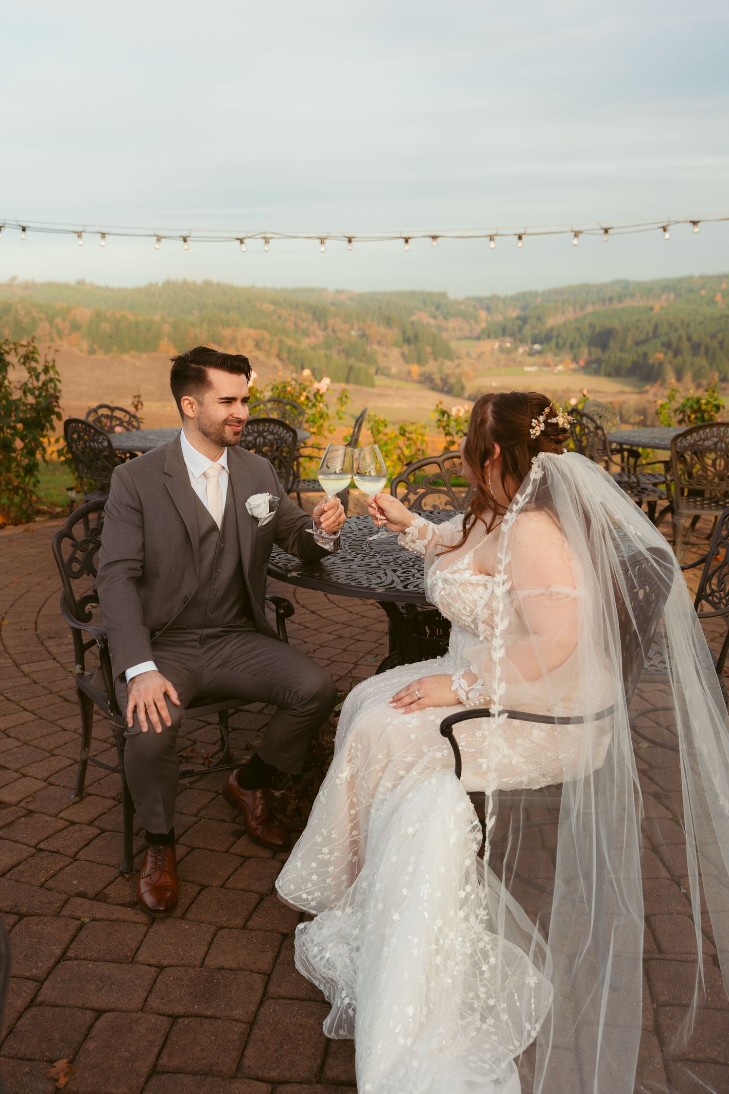 Bride and groom share candid interactions during outdoor wedding photo session at dusk.