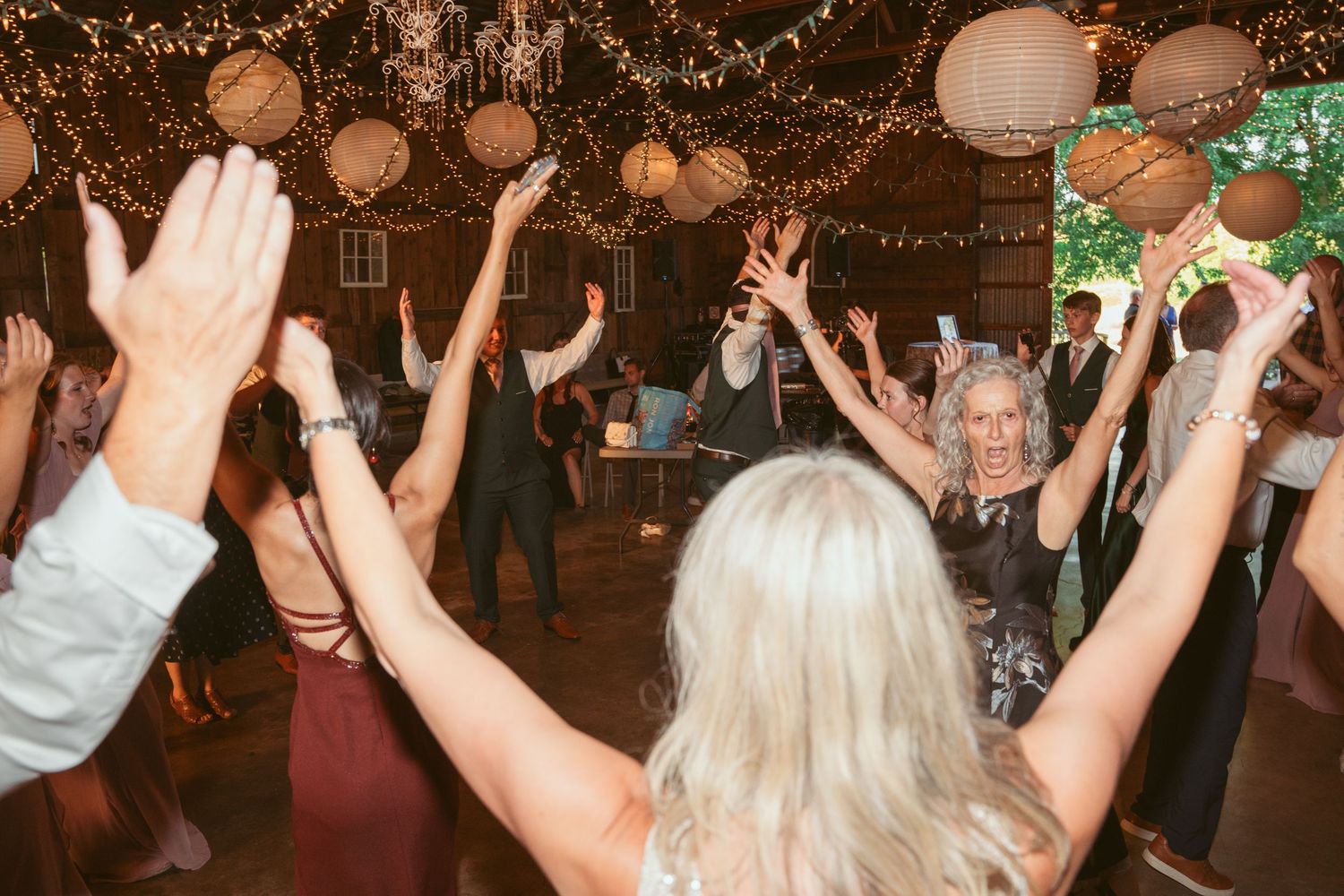 Celebration in a barn with dancers under twinkling lights and paper lanterns.