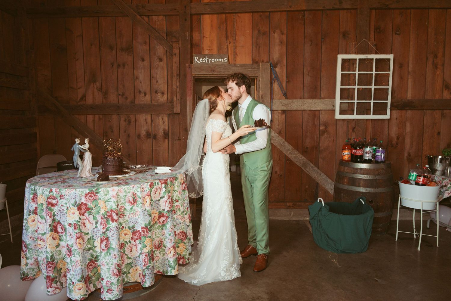 Couple celebrates with cake at their barn wedding reception.