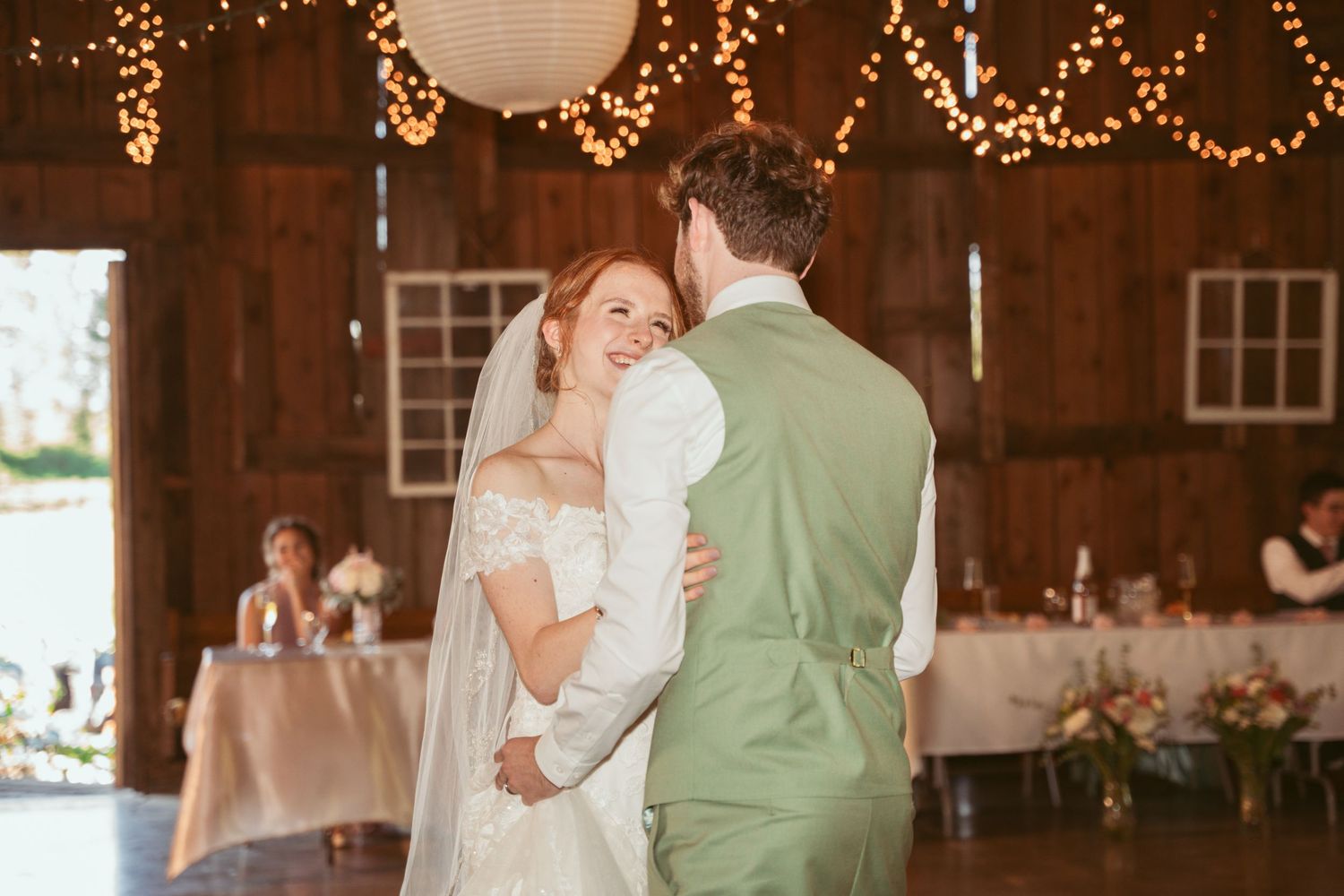 Romantic dance moment at a barn wedding reception with string lights overhead.