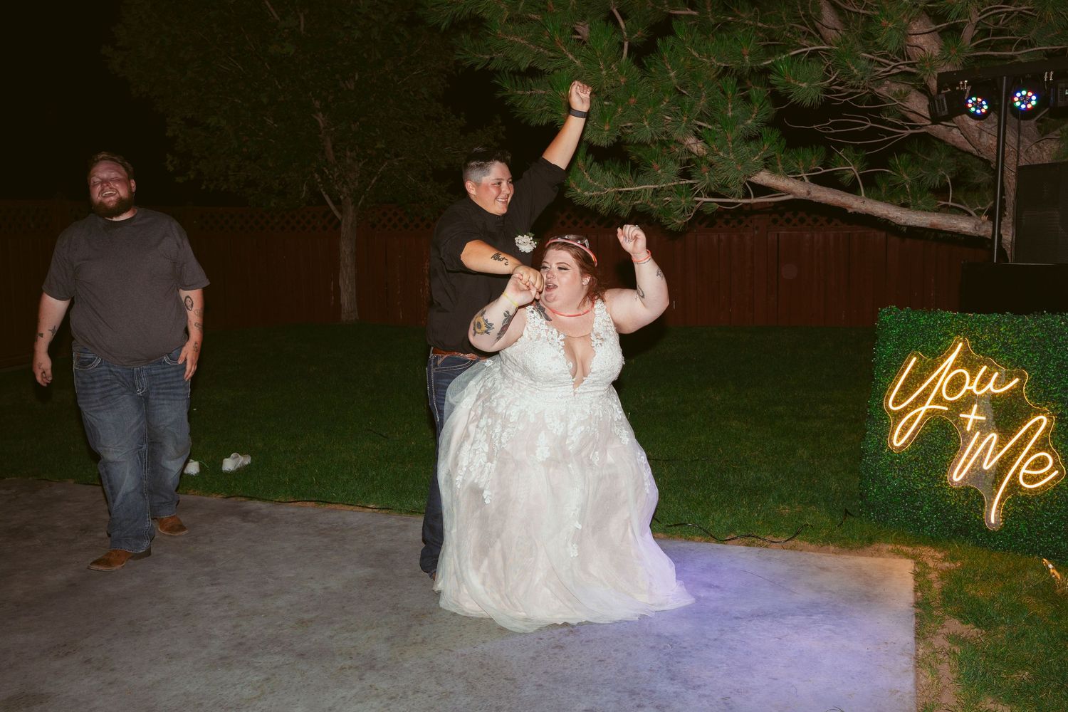 Wedding celebration at night with a neon sign glowing in the background.