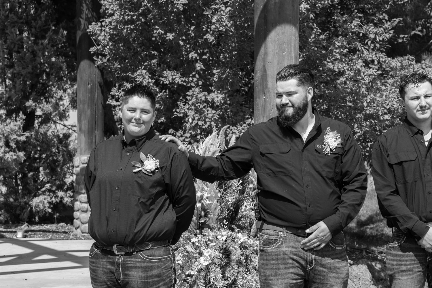 Black and white photo showing a line of groomsmen standing together outdoors.