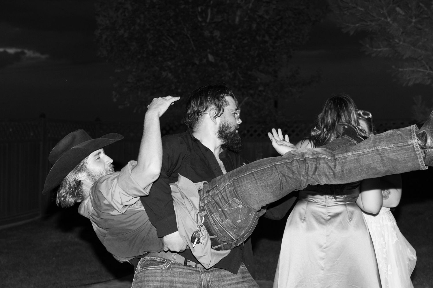 Black and white photo of energetic dancing at nighttime wedding reception.