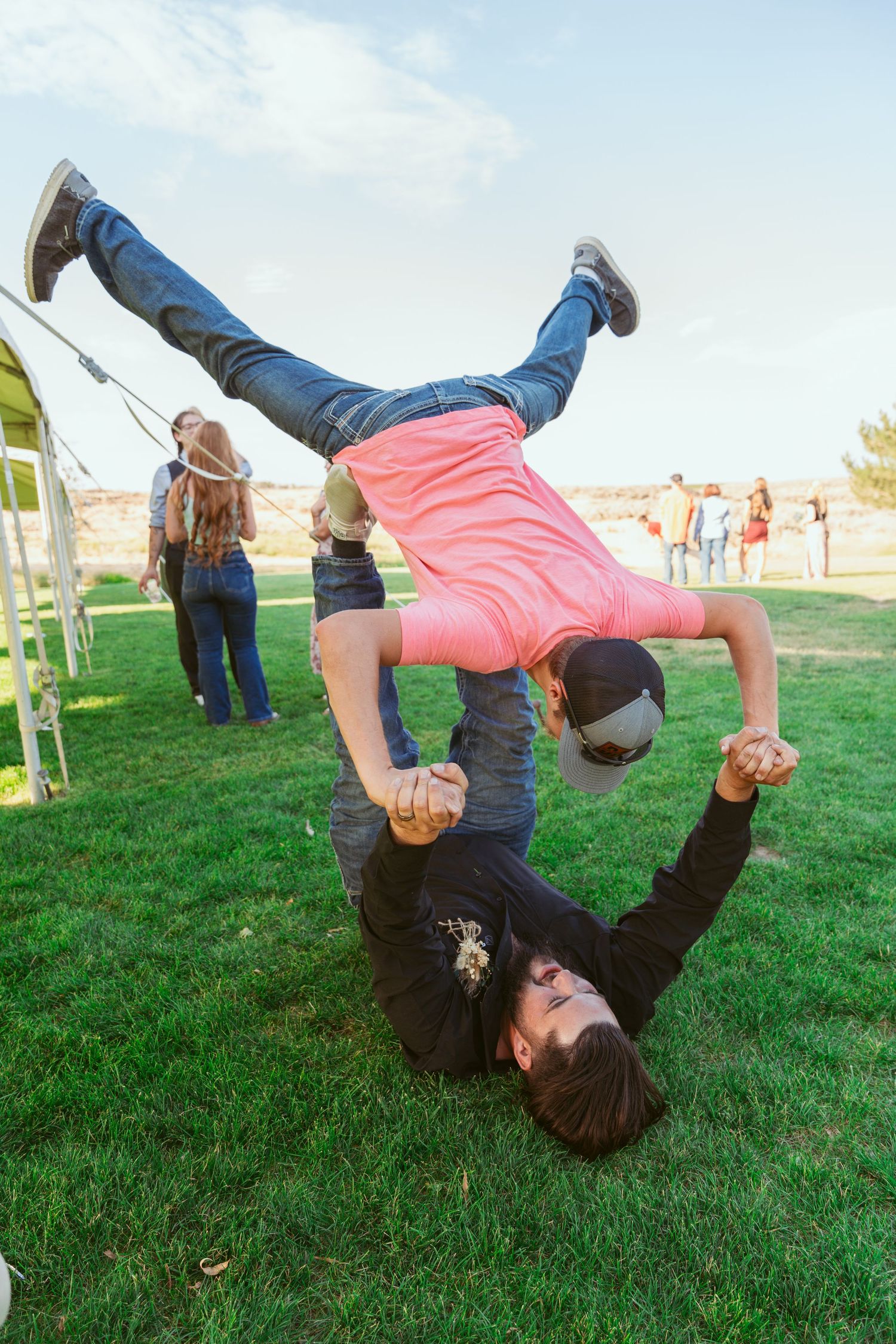Two people performing an acrobatic stunt on grass with one balancing upside down.